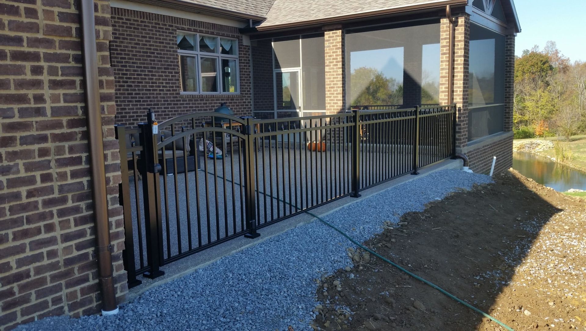 Brick house porch with black metal railings and a gravel path along the side.
