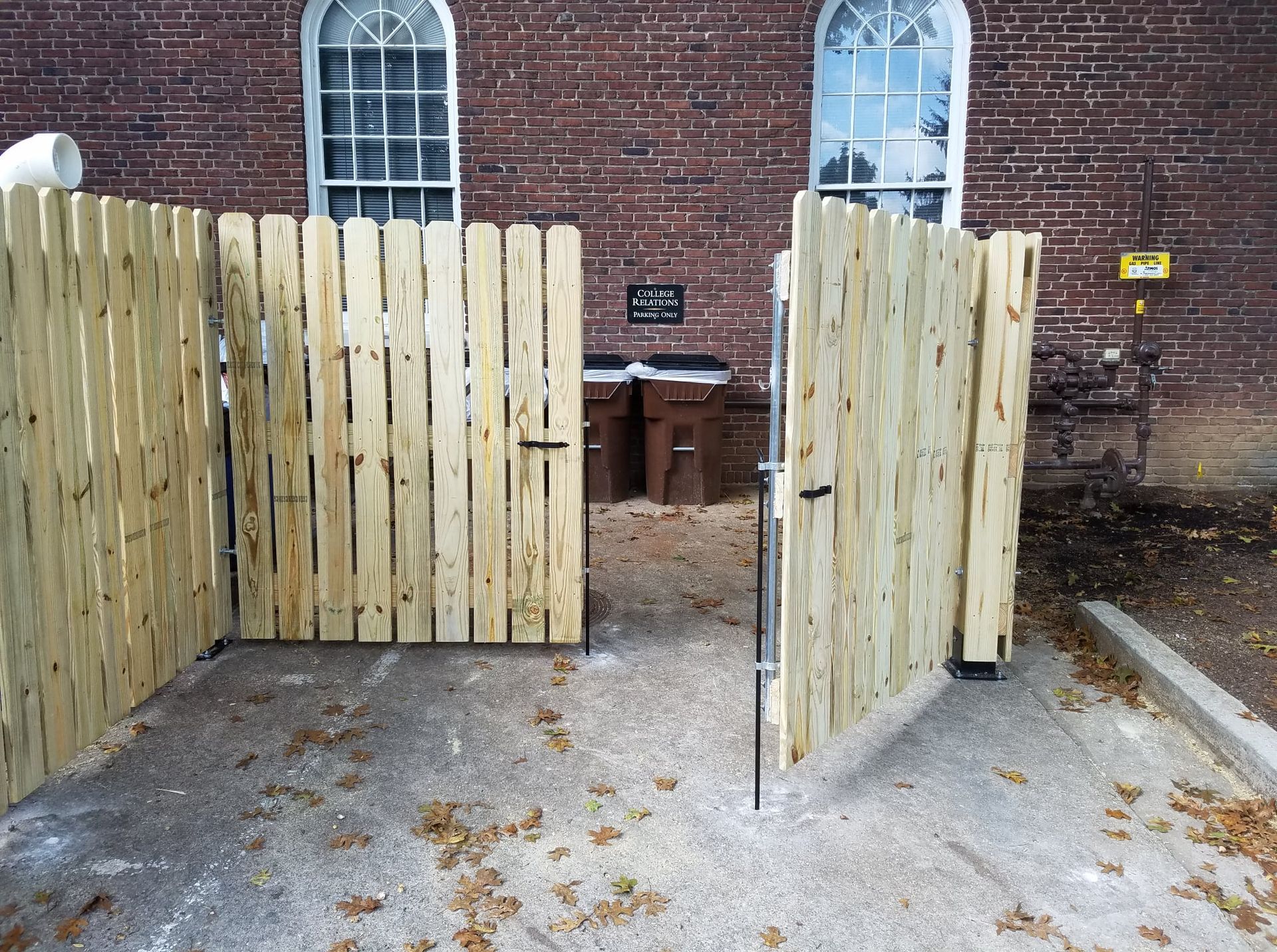 Open wooden gate in a brick-walled courtyard with tables behind it