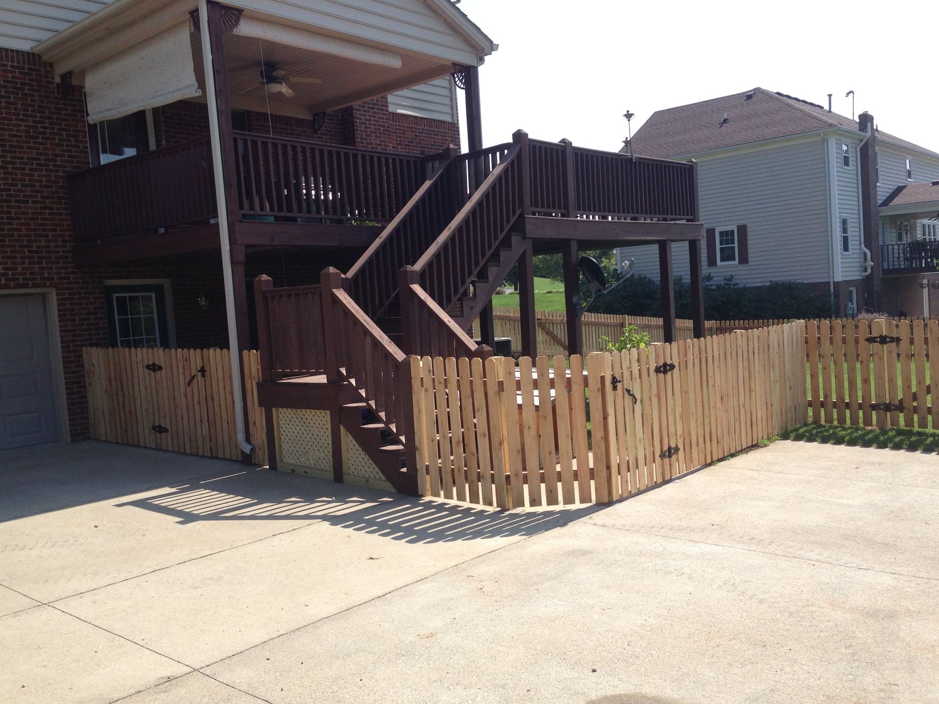 Wooden house deck with stairs and a small fenced yard beside a driveway
