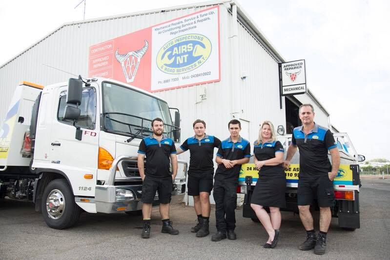 Five staff in black uniforms stand beside a white delivery truck outside a warehouse — Auto Inspections & Road Services N.T. in Woolner, NT