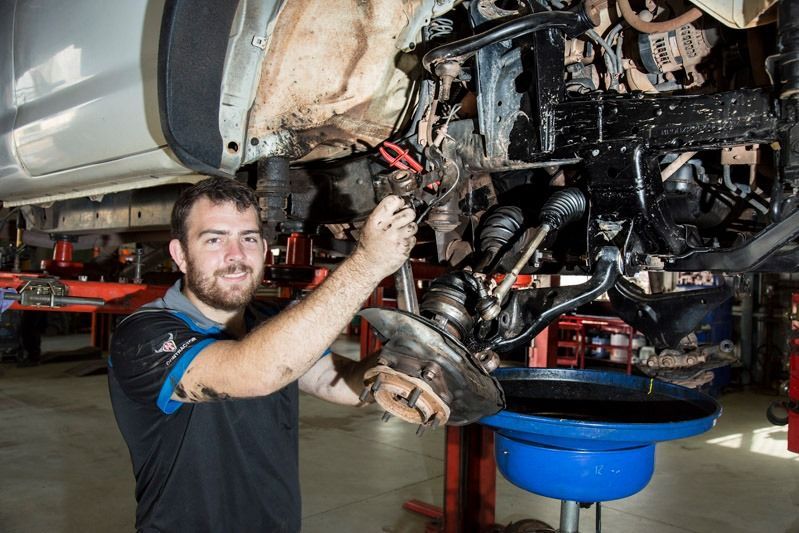 A Mechanic In A Garage Working On The Suspension And Wheel — Auto Inspections & Road Services N.T. in Woolner, NT