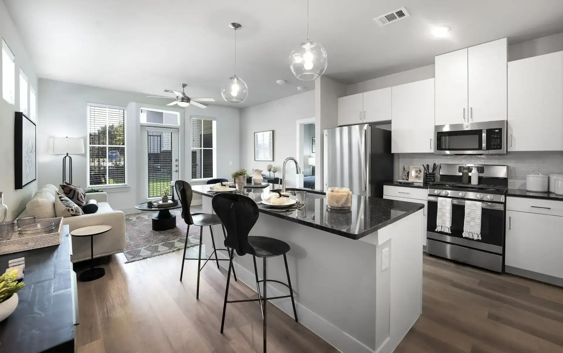 Modern apartment interior with kitchen island, stainless steel appliances, and living area.