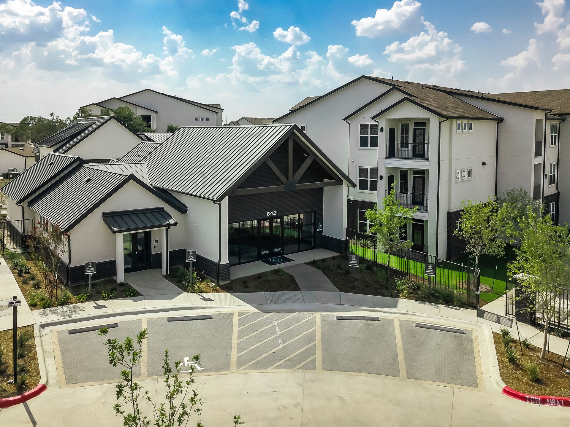 An aerial view of a large apartment leasing office building with a parking lot in front of it at The Gabriel in Leander, TX.