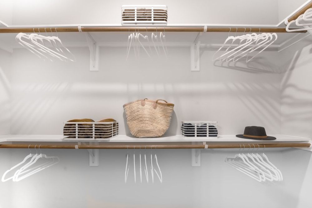 A walk-in closet with shelves filled with clothes and hats at The Gabriel, which offers apartments in Leander, TX, near Tesla.