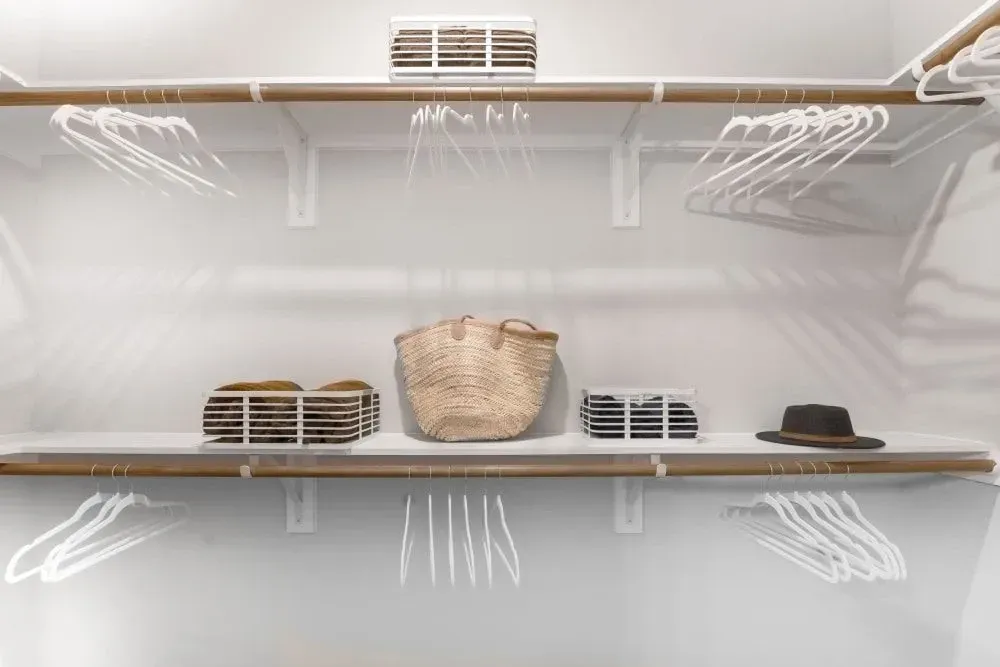 A walk-in closet with shelves filled with clothes and hats at The Gabriel, which offers apartments in Leander, TX, near Tesla.