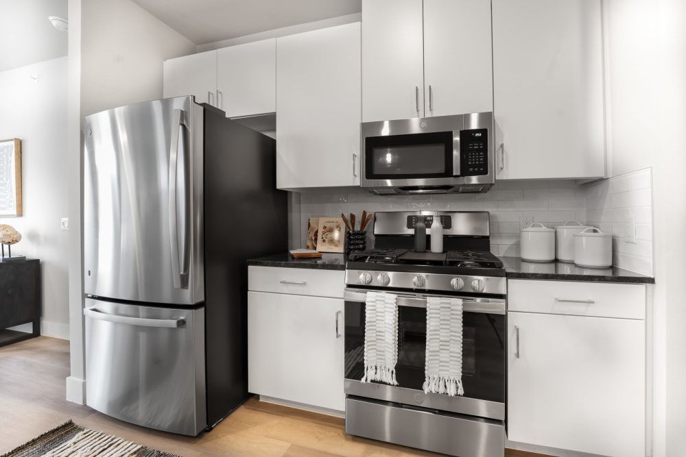 Apartment kitchen with stainless steel appliances, a gas stove, designer lighting, and a large island at The Gabriel, which offers apts in Leander, TX.