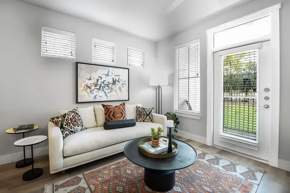 Spacious apartment living room with a couch, coffee table, and sliding glass door to an outdoor patio at The Gabriel, which offers pet-friendly apartments in Leander.