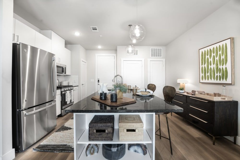A kitchen with stainless steel appliances and a large island in the middle with storage and bar seating at The Gabriel, which offers apartments for rent in Leander.