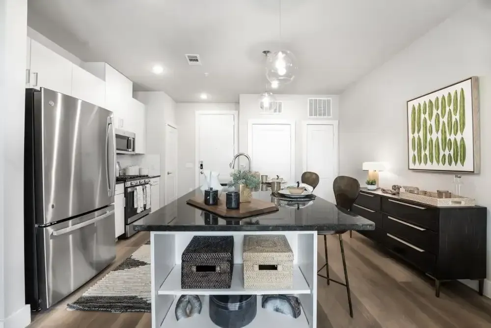 A kitchen with stainless steel appliances and a large island in the middle with storage and bar seating at The Gabriel, which offers apartments for rent in Leander.