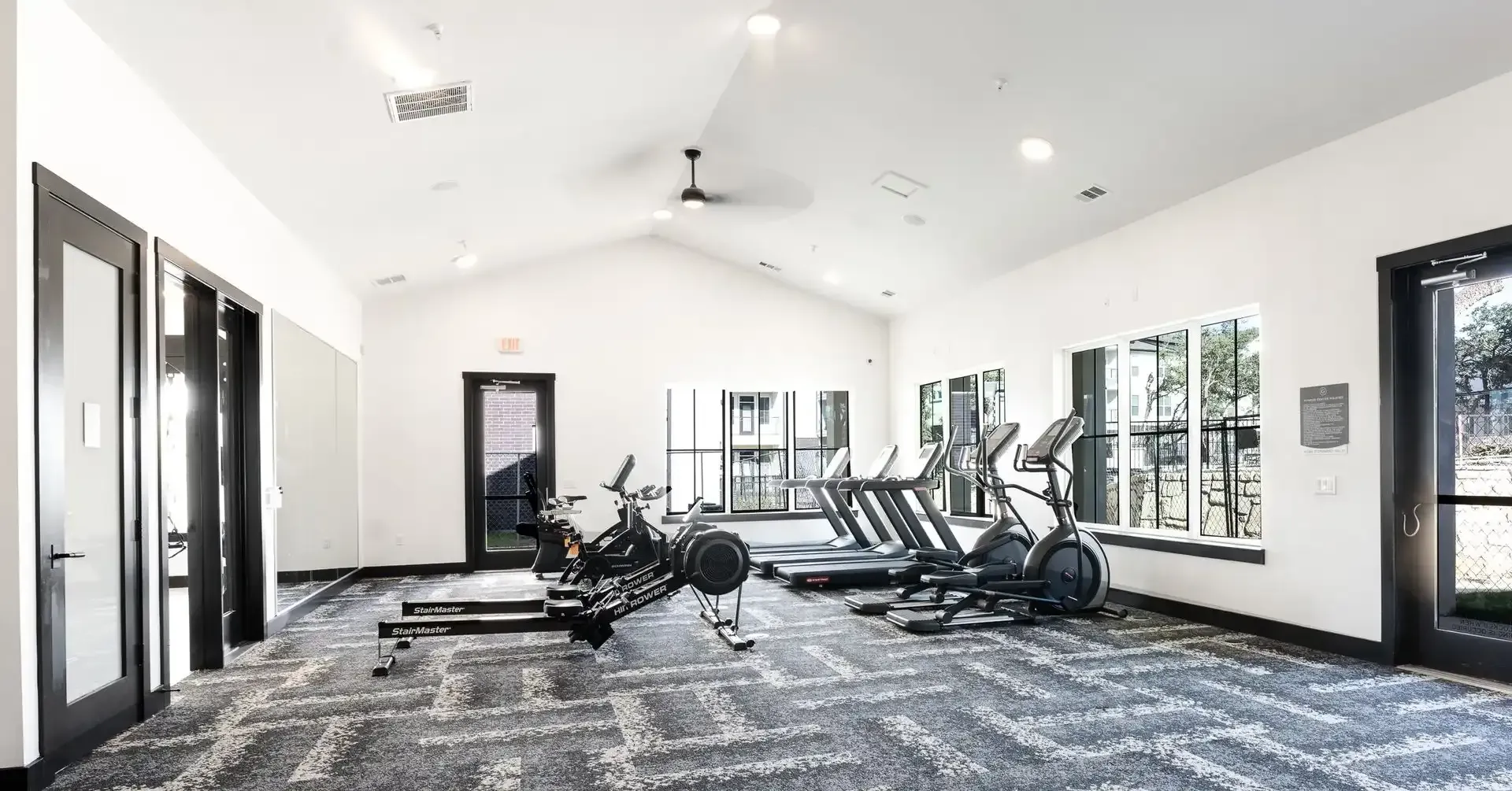 Apartment gym with a lot of exercise equipment and a ceiling fan at The Gabriel, which offers luxury apartments near Georgetown.