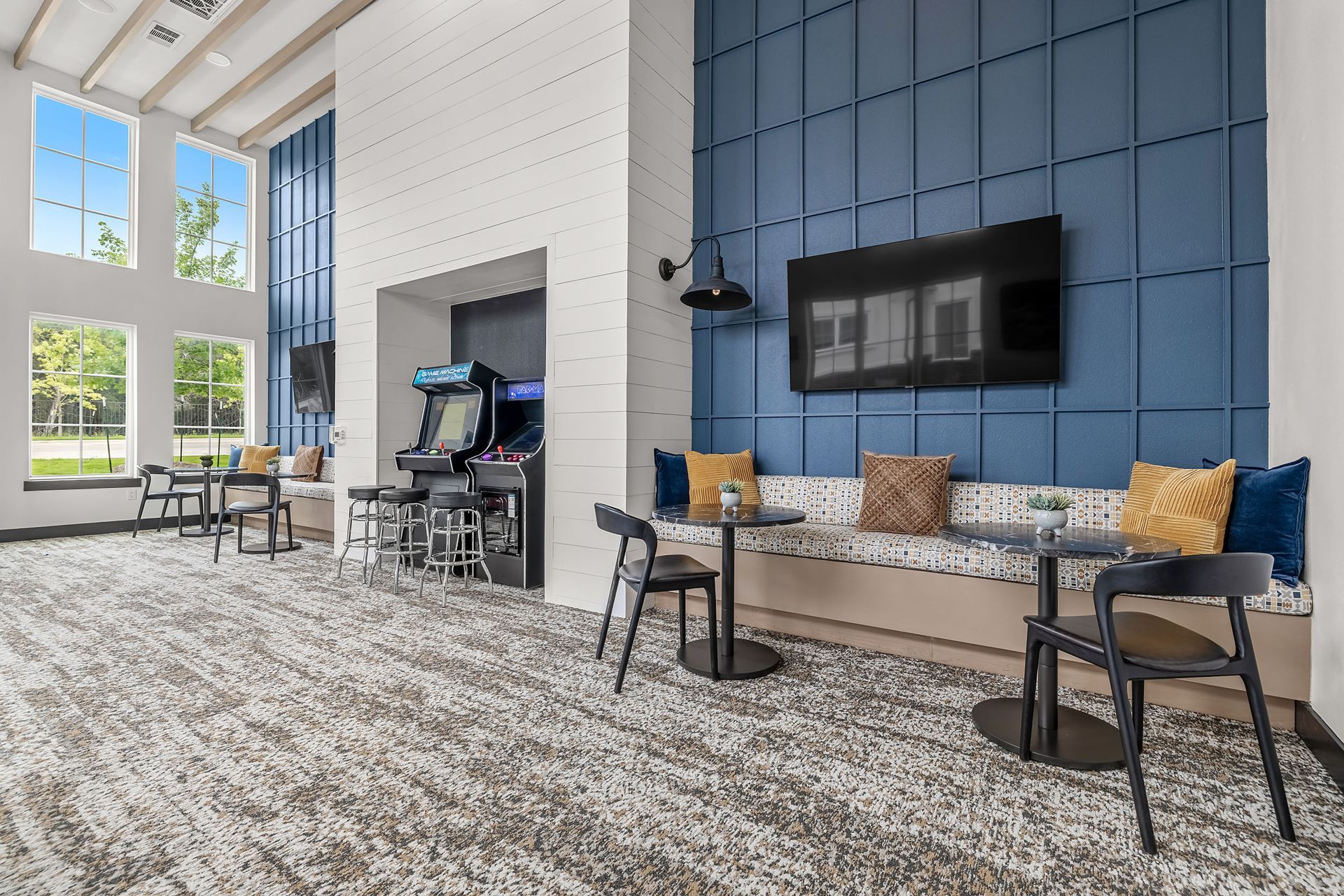 Game room with tables and chairs, game machines, and a TV at The Gabriel, which offers apartments for rent in Leander, TX, near The Domain.