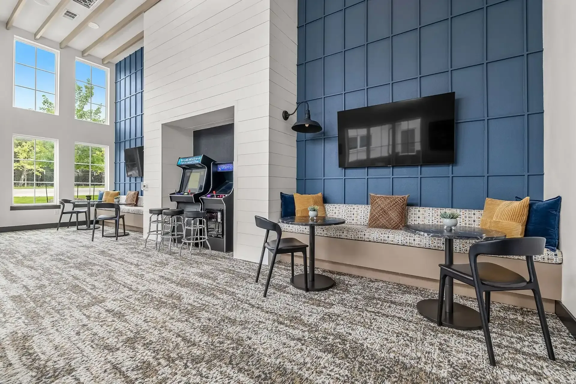Game room with tables and chairs, game machines, and a TV at The Gabriel, which offers apartments for rent in Leander, TX, near The Domain.