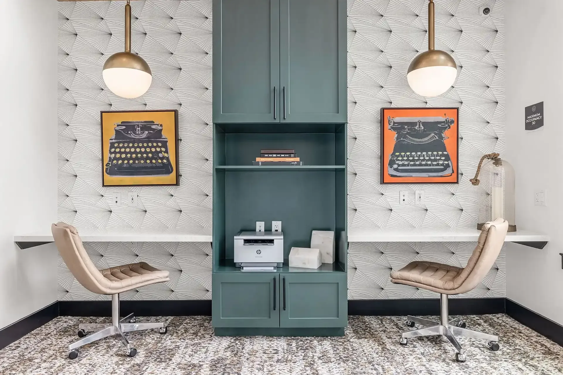 Apartment community work pod with a bench, table, chair, and painting on the wall at The Gabriel, which offers new apartments for rent in Leander, TX.
