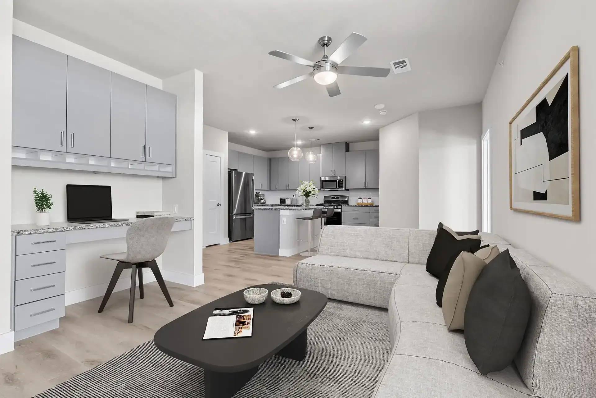 Open floor plan with a kitchen and living room, including a couch, coffee table, and workspace, at The Gabriel, which offers apartments near Cedar Park, TX.