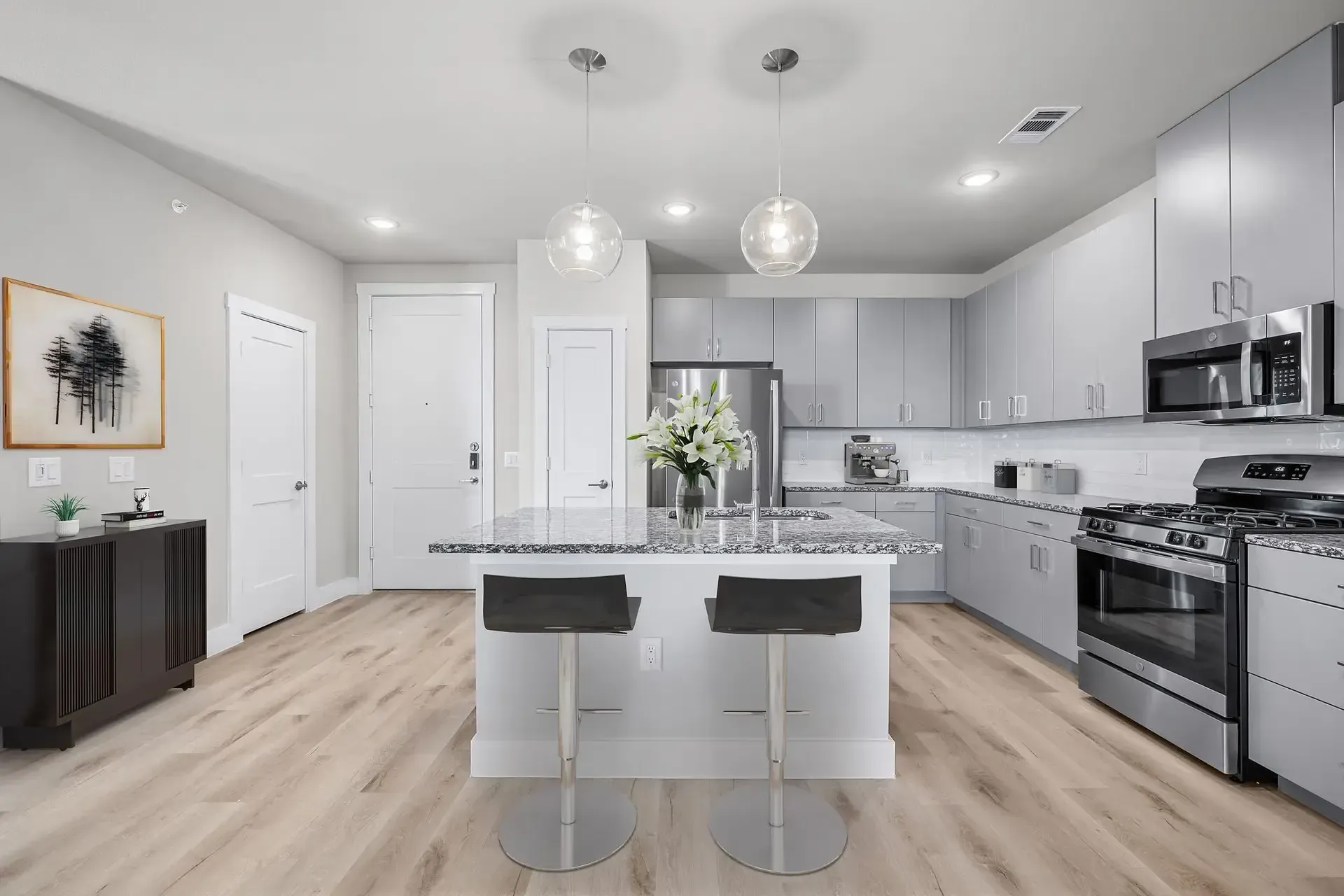 Apartment kitchen with stainless steel appliances, a gas stove, designer lighting, and a large island at The Gabriel, which offers apts in Leander, TX.