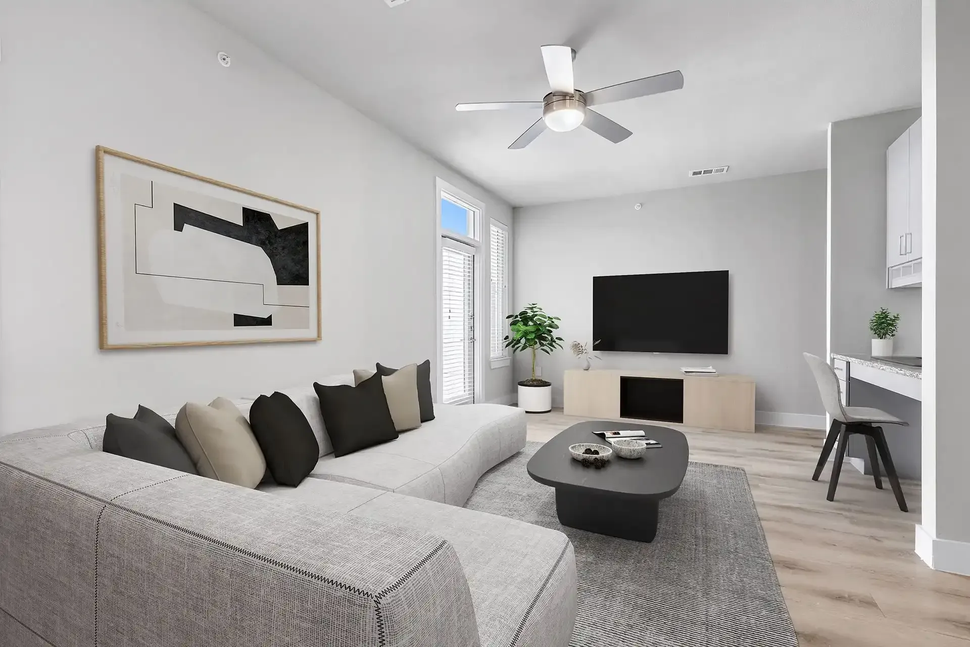 Modern living room at The Gabriel featuring a couch, coffee table, television, and ceiling fan. The Gabriel offers pet-friendly apartments in Leander, TX.