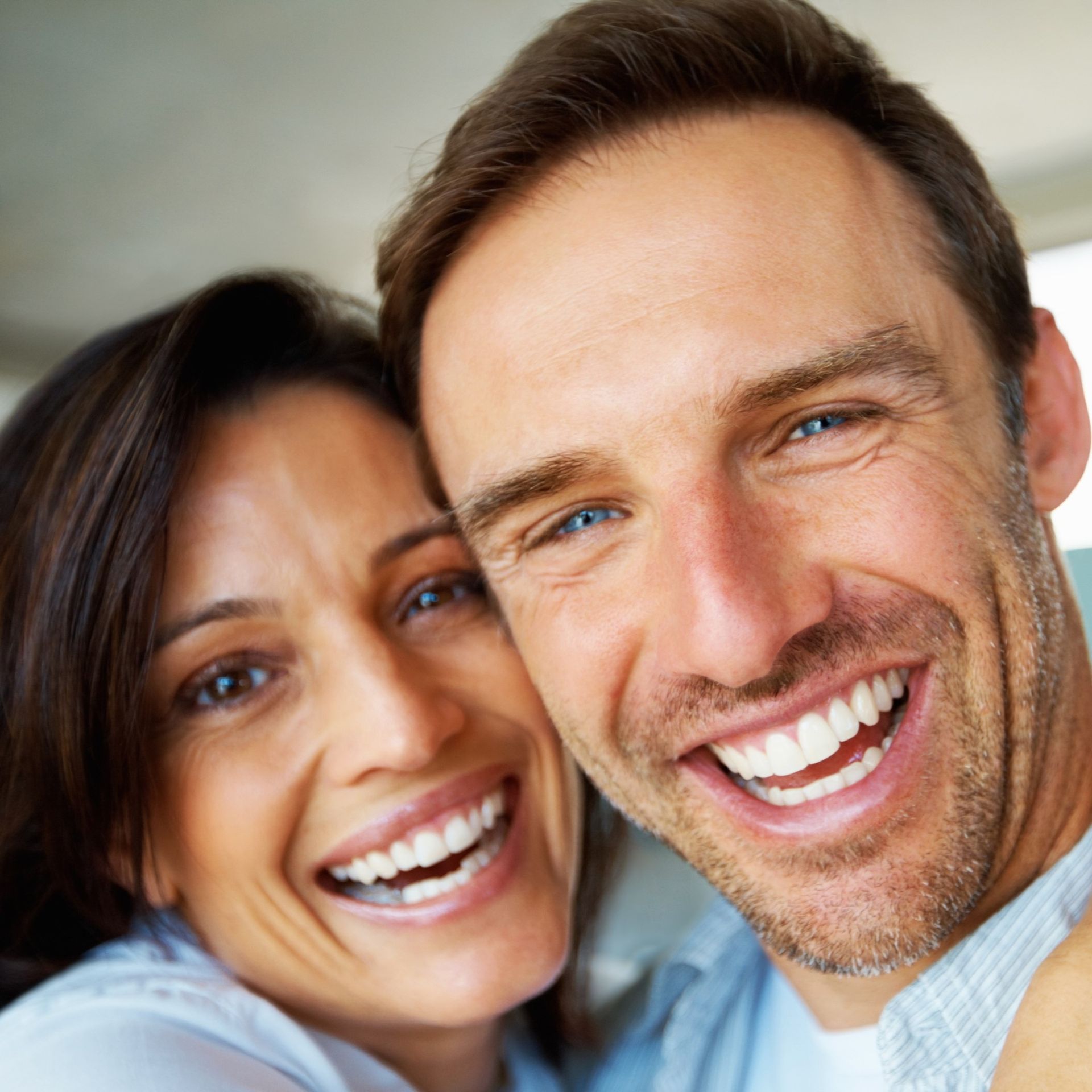Smiling couple, the woman with dark hair and the man with blue eyes, close-up.