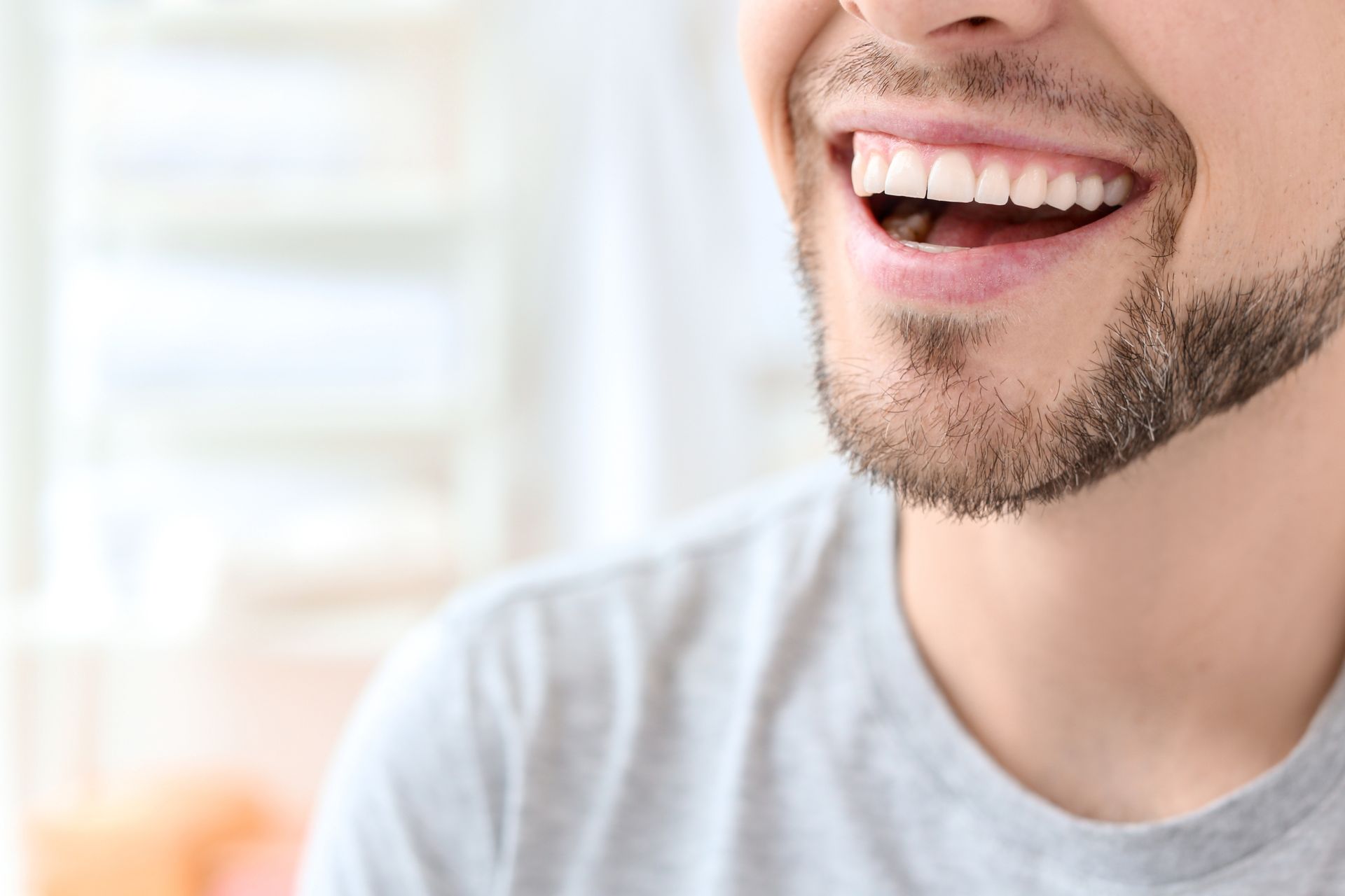 Close-up of a smiling man with a short beard, showing white teeth.