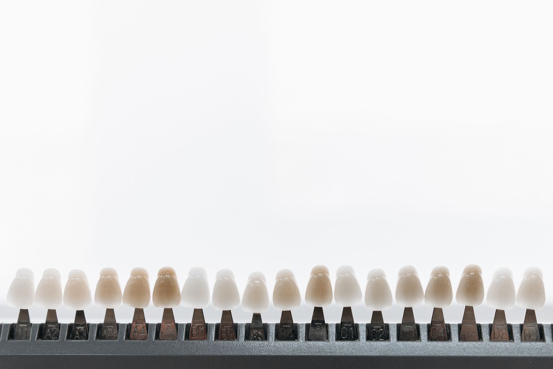 Tooth shade guide with a range of tooth color samples on a black base, against a white background.