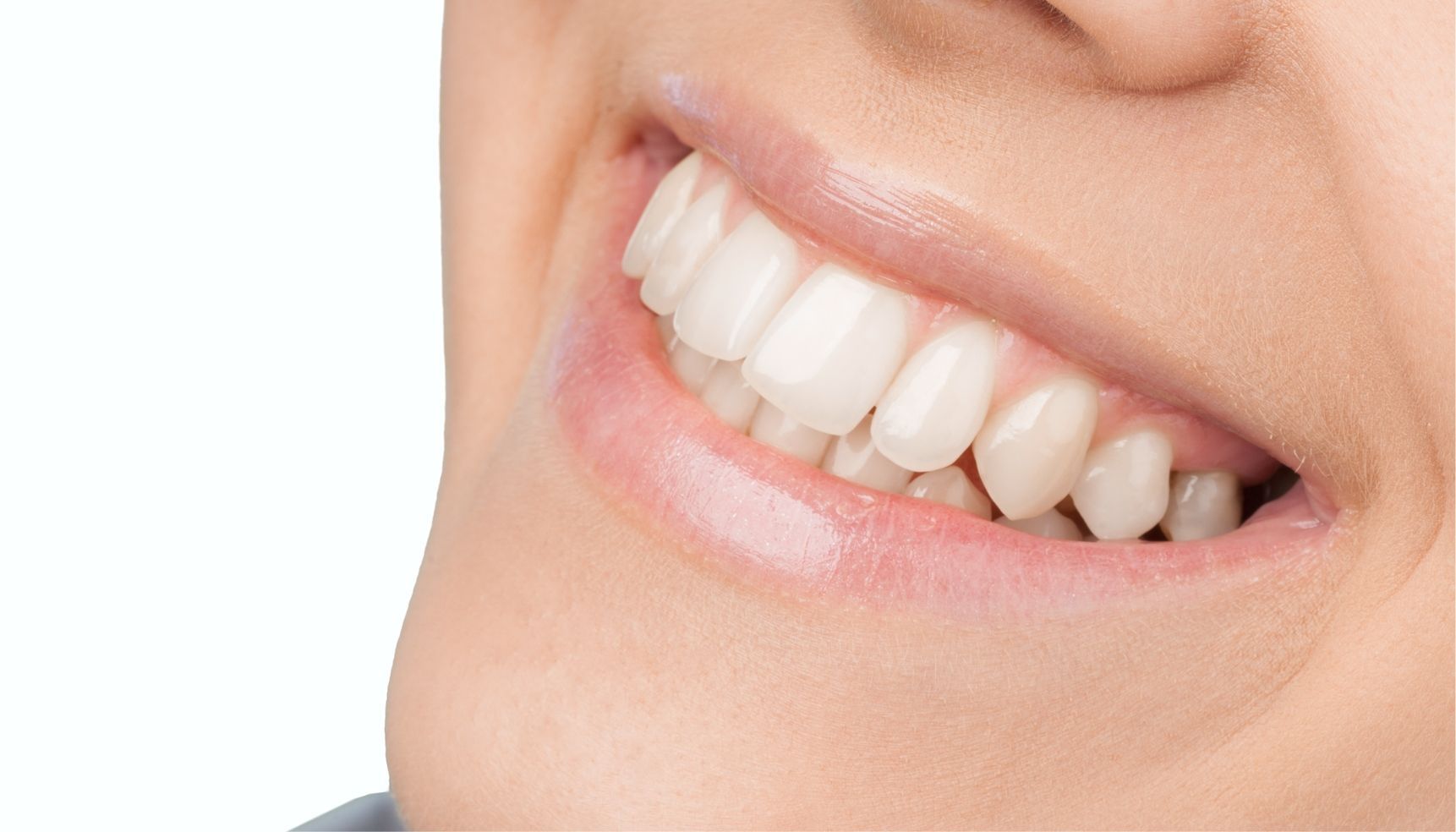 Close-up of a smiling person's mouth showing healthy, white teeth and pink lips.