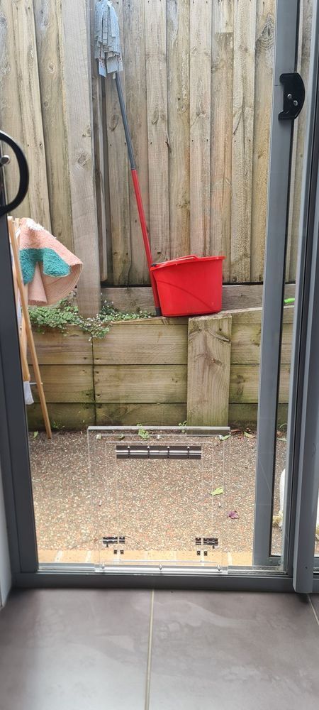 A red mop and bucket are sitting on a wooden fence.