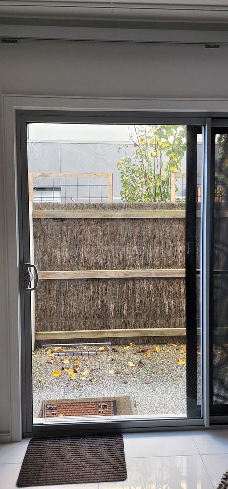 A sliding glass door is open to a fence in a living room.