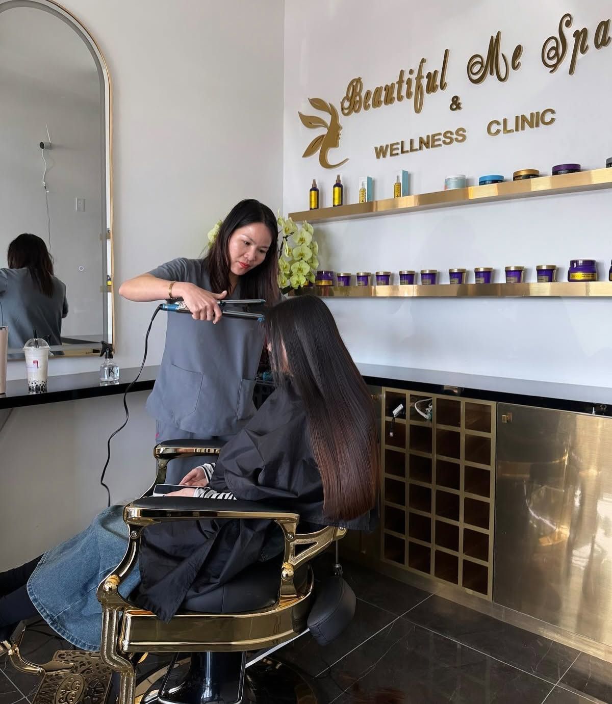 Stylist cutting hair in a wellness clinic salon with mirrored wall and product shelves
