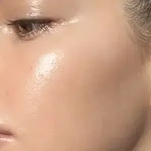 Close-up of a face with glossy cheek makeup and a closed eye