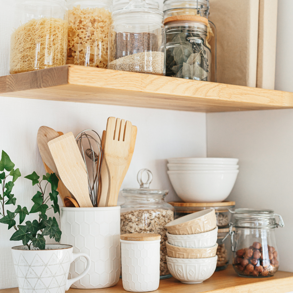A wooden shelf filled with bowls , jars , and utensils.