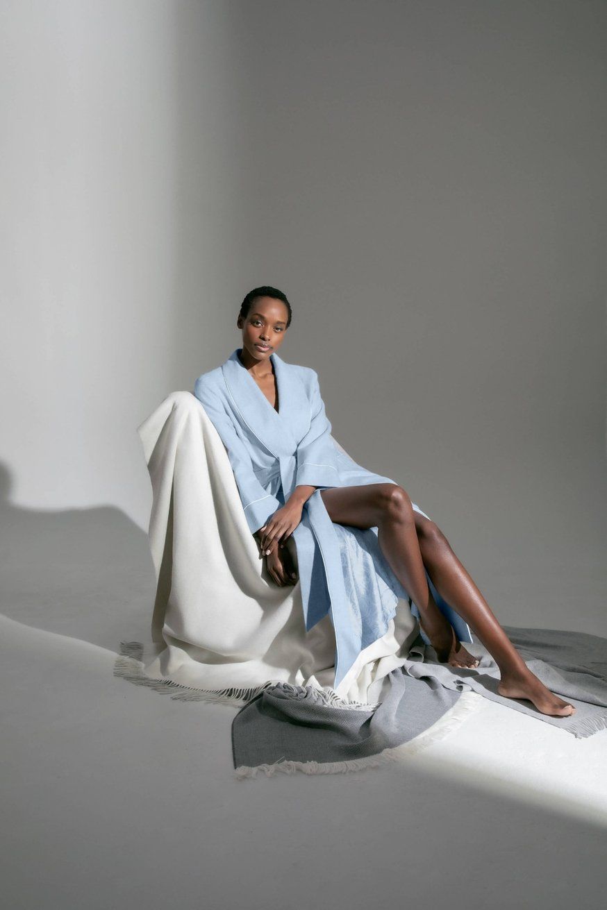 A woman in a blue robe is sitting on a white chair.