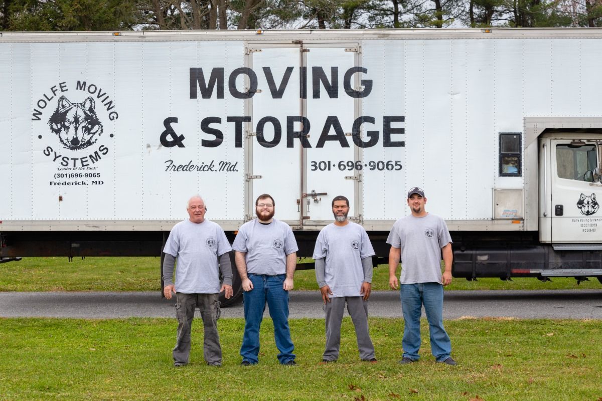 A group of men are standing in front of a moving and storage truck.