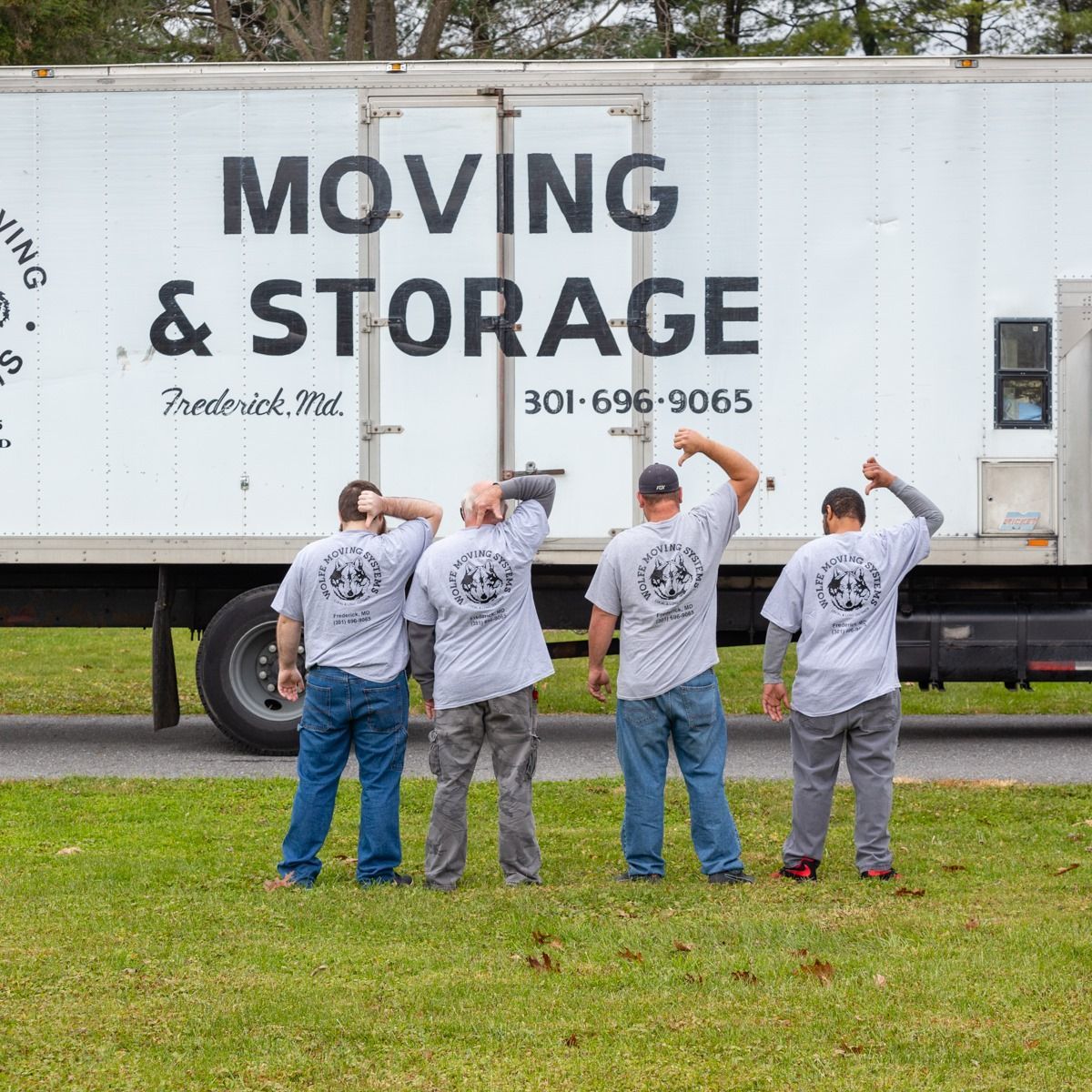 Four men are standing in front of a moving and storage truck.