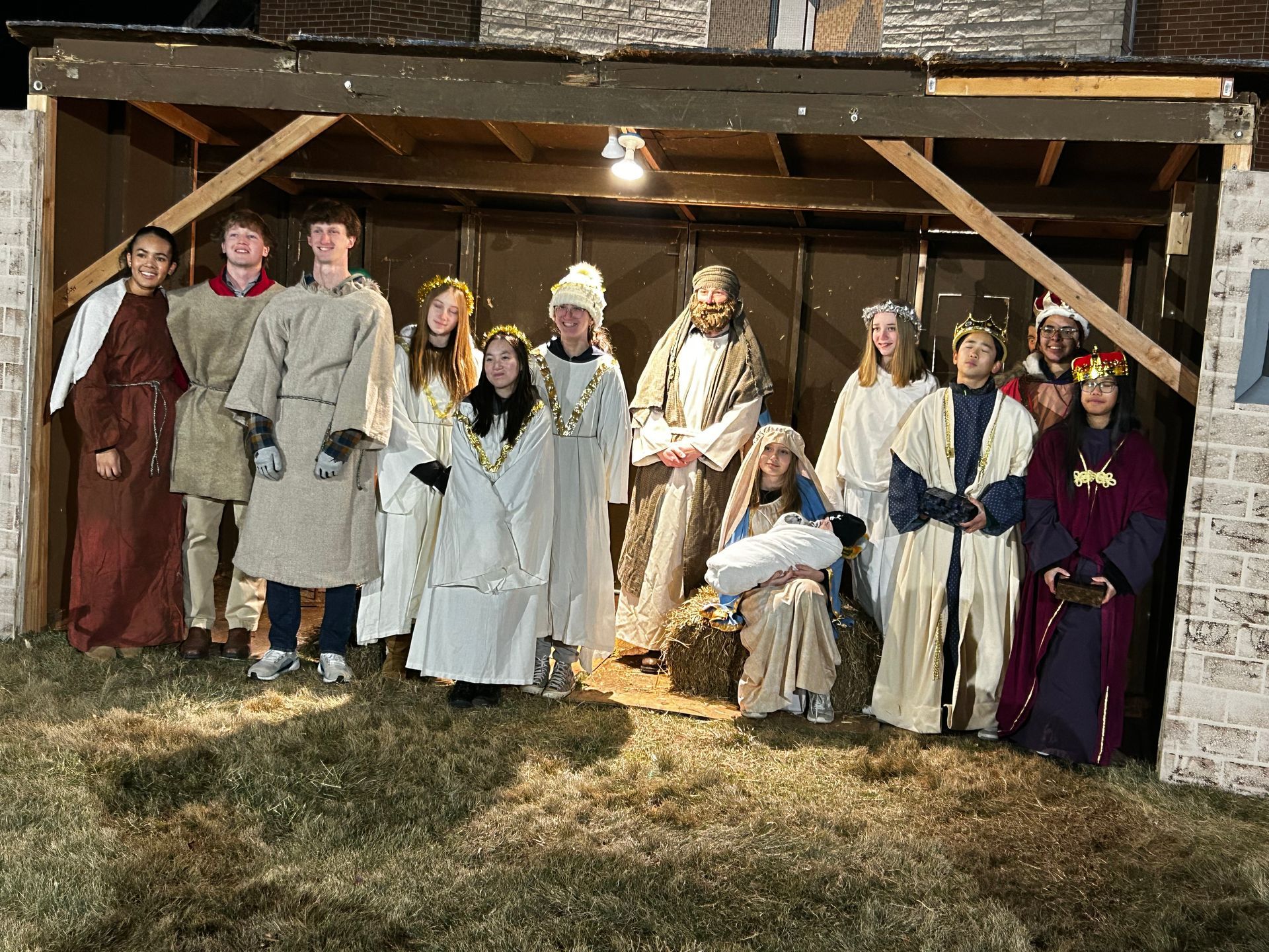 A Christmas nativity scene with costumed teens posing in a manger.