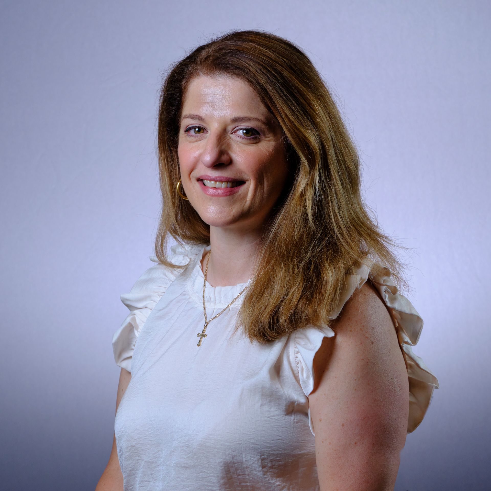 Woman with long blonde hair and white top smiles at the camera.