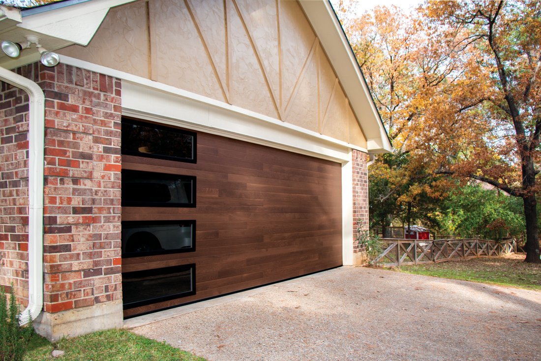 A wooden garage door is sitting in front of a brick house.