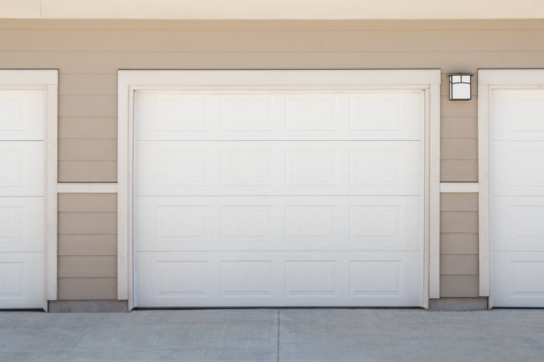 A row of white garage doors on the side of a house.