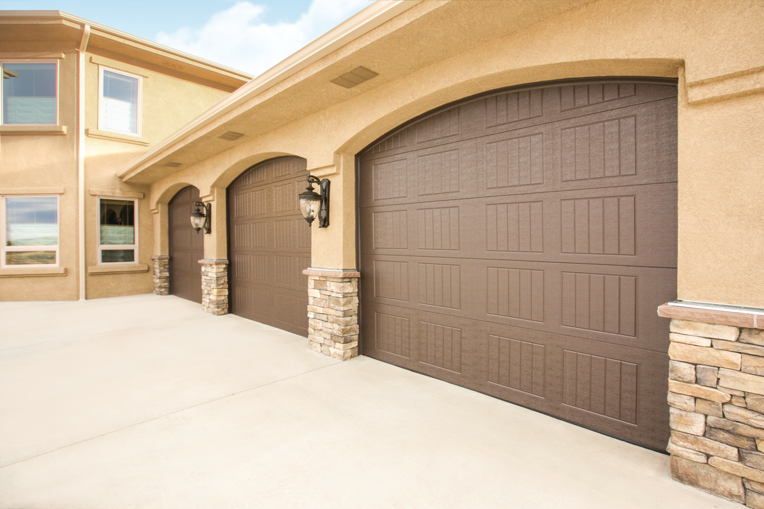 A row of brown garage doors on the side of a house.