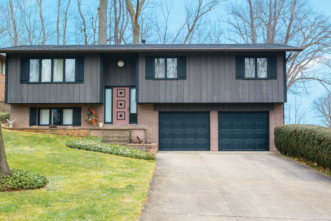 A large house with two garage doors and a driveway.