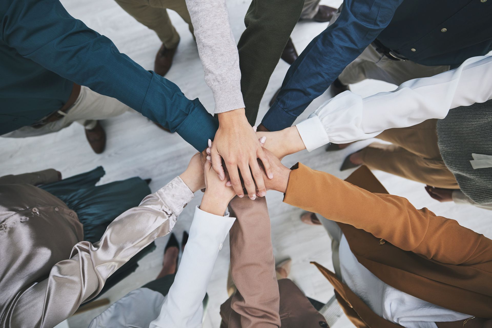 A group of people are putting their hands together in a circle.
