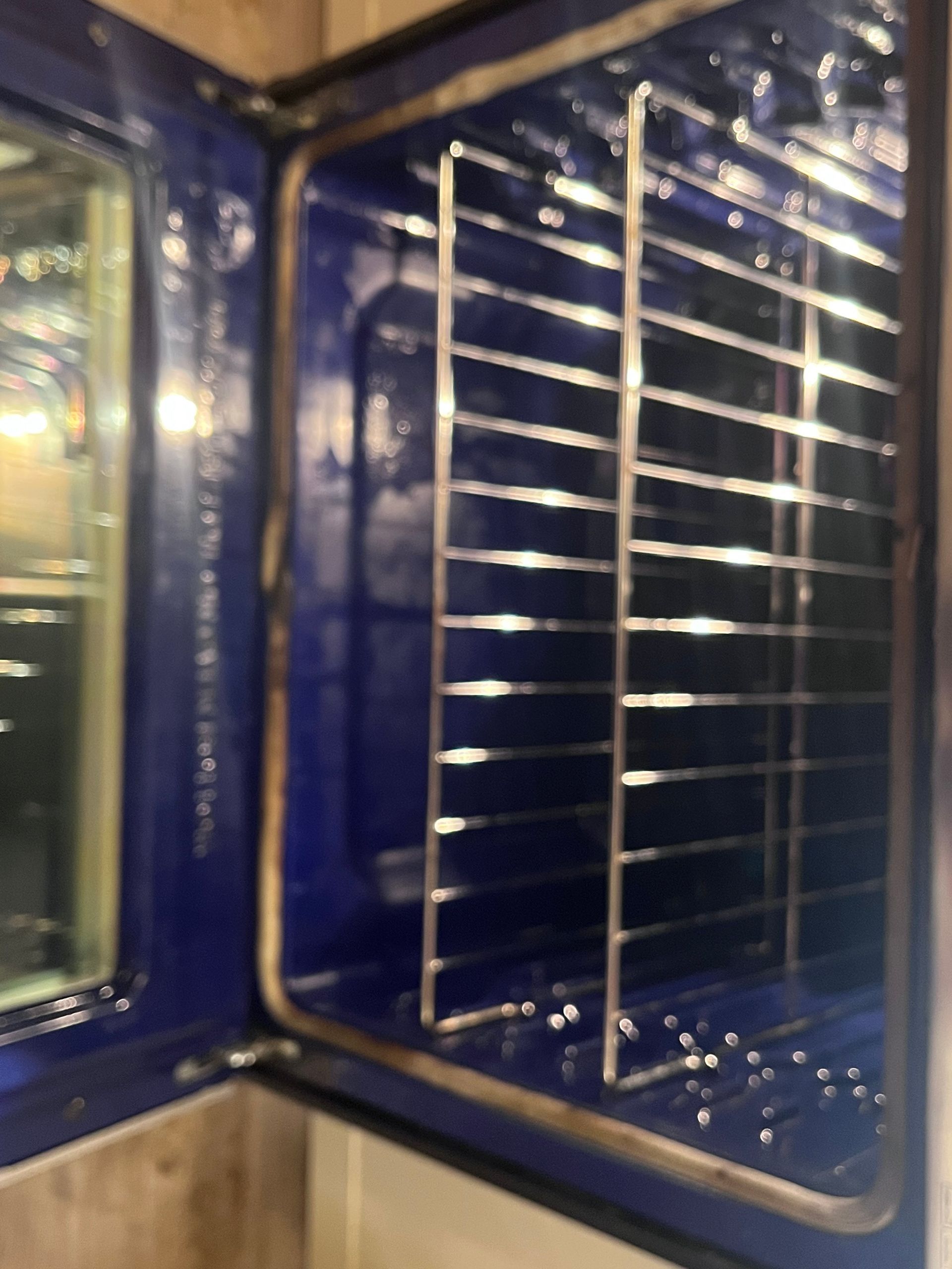 Open oven interior with blue enamel walls and metal racks.