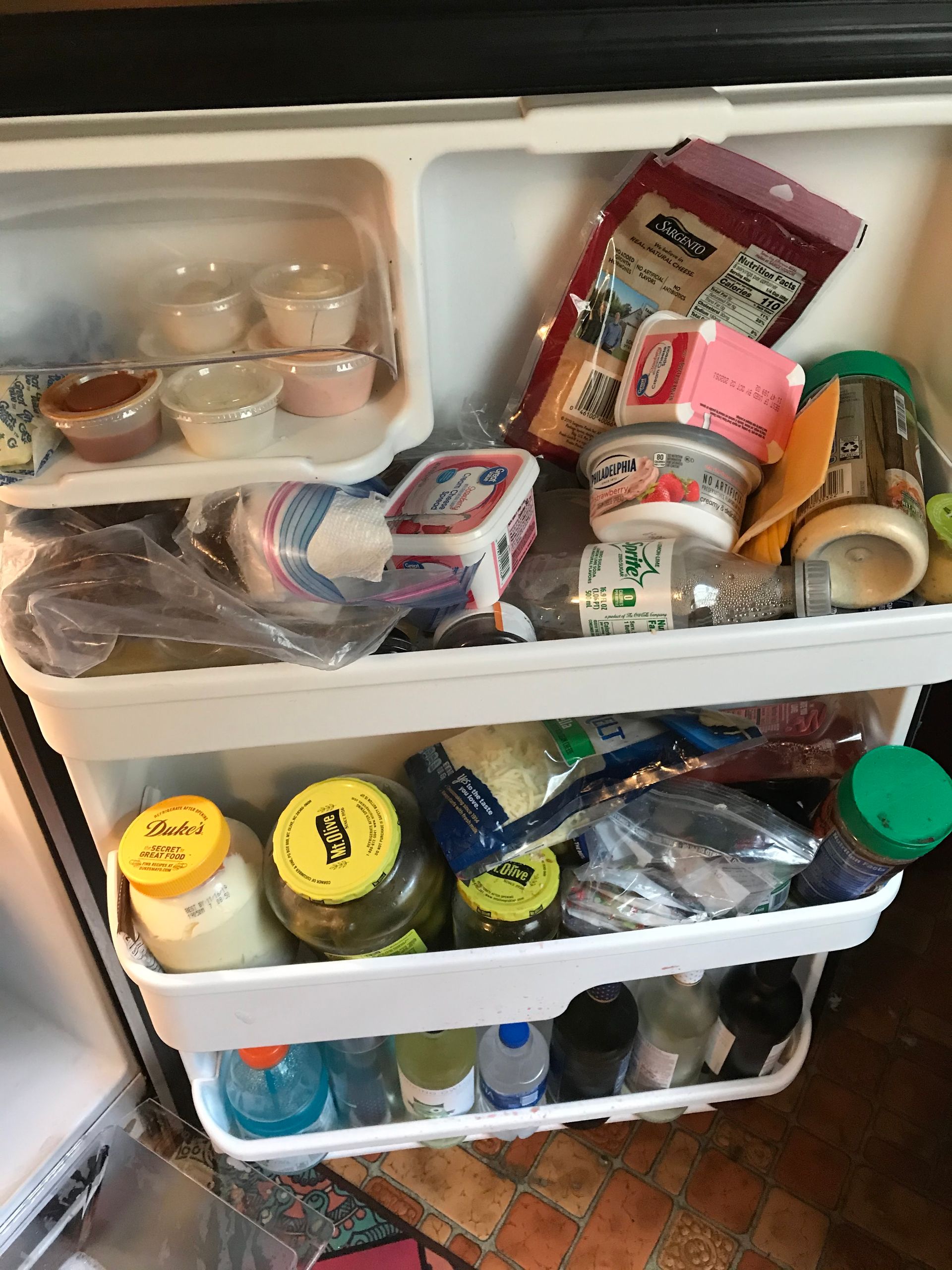 A refrigerator interior filled with various food items in containers and packages. There are jars.