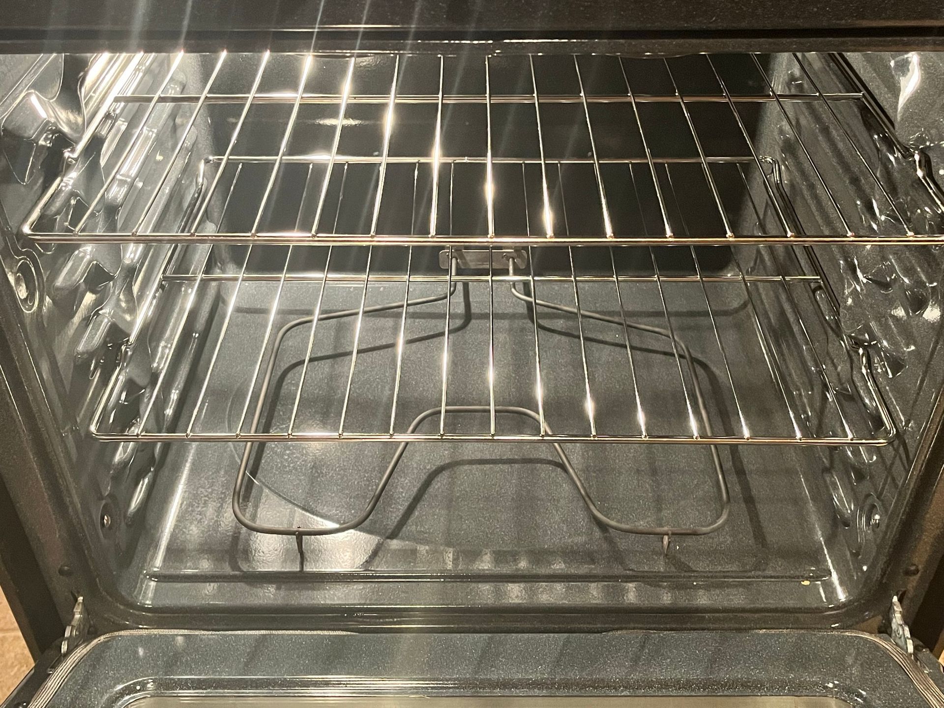 Interior view of a clean, empty oven with two racks and a broiler pan, ready for use.