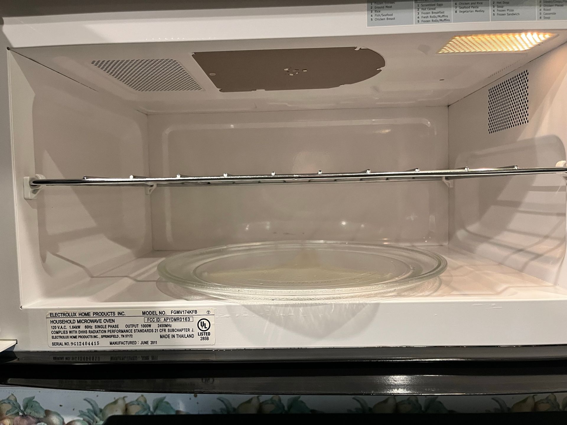 Inside of a white microwave with a glass plate on the bottom and a metal rack above. The interior is mostly clean.