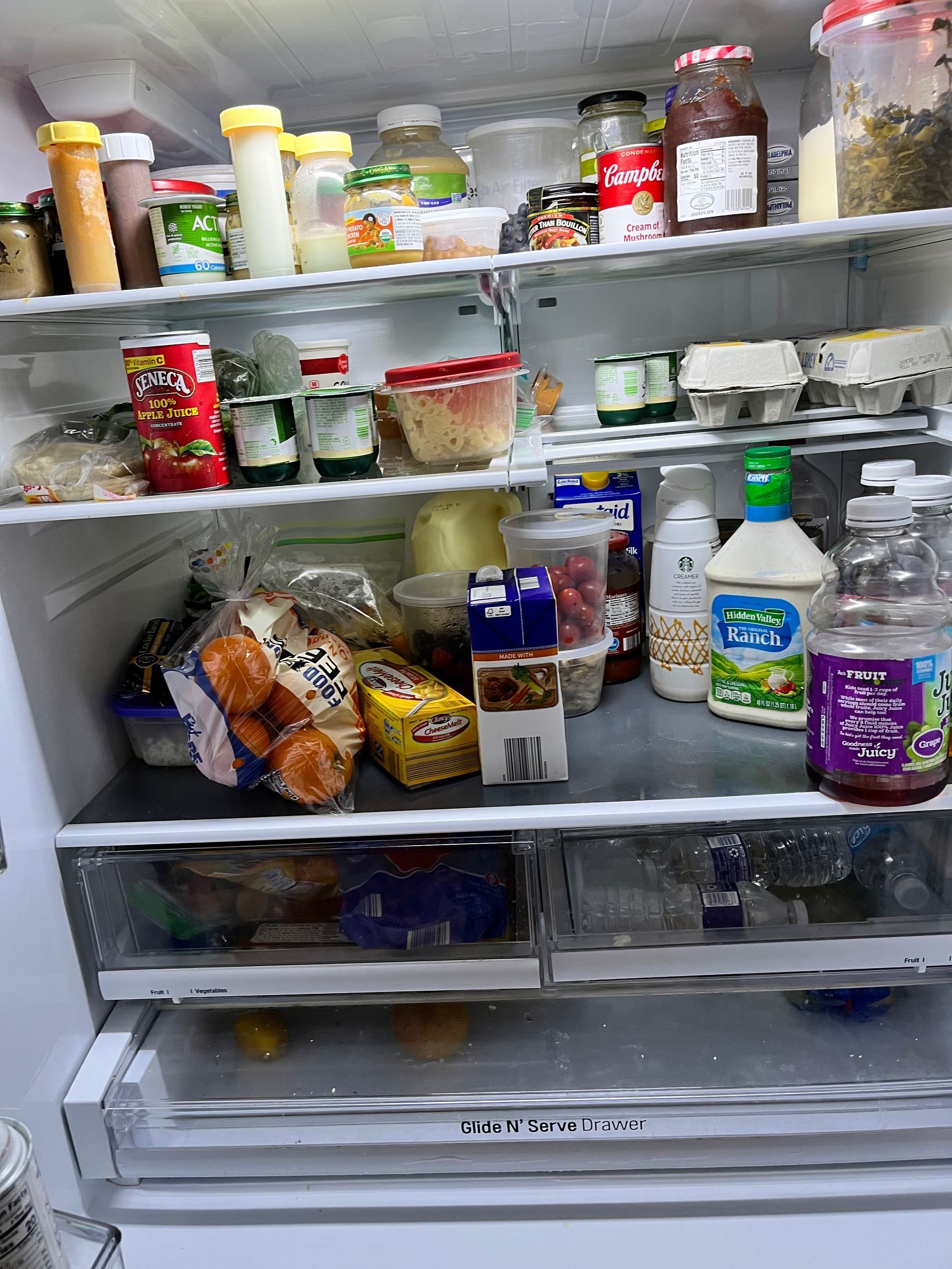 Refrigerator interior with various food items on shelves, including condiments, eggs, and packaged goods.