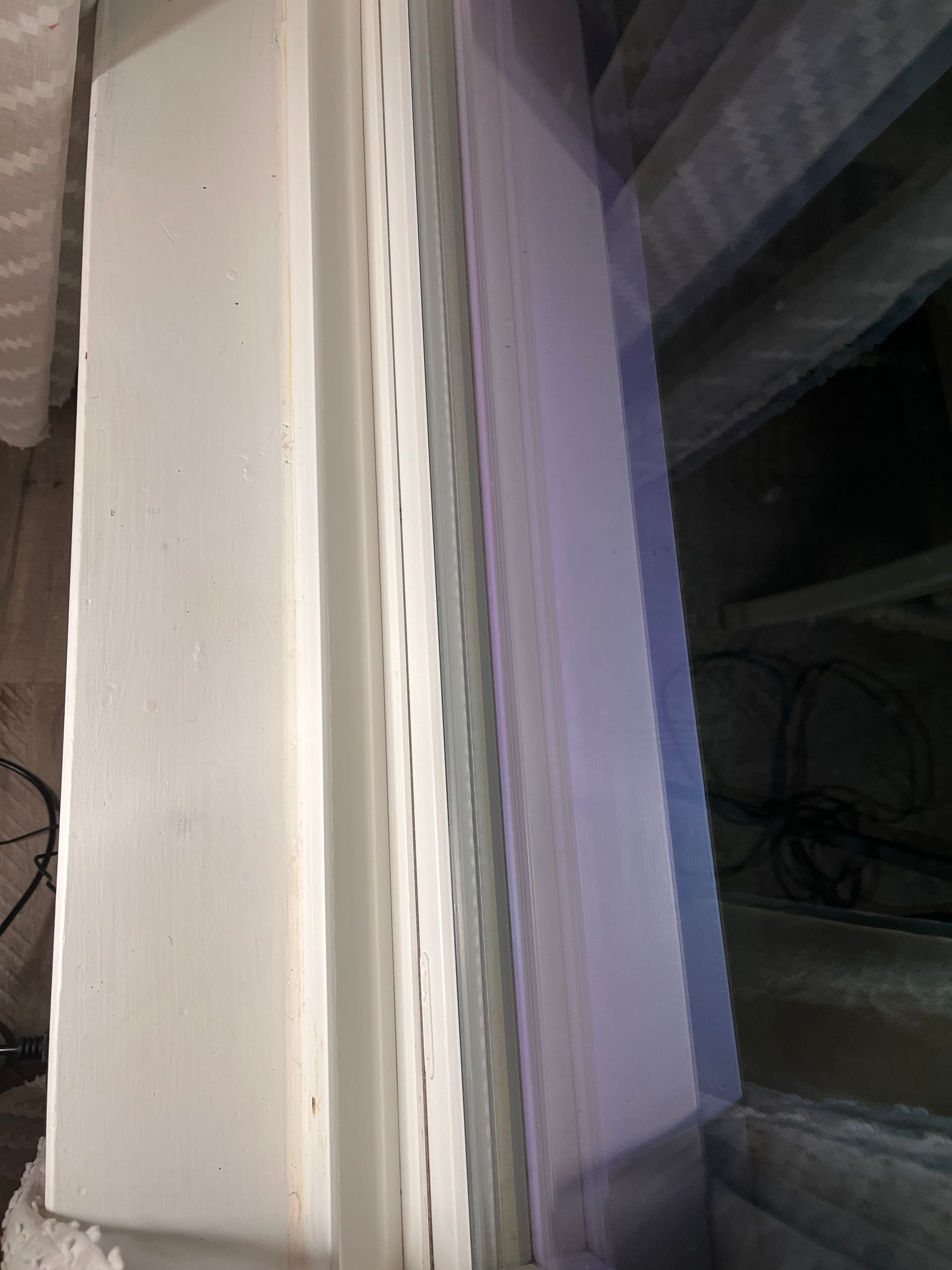 White window frame with ventilation siding next to a wall.