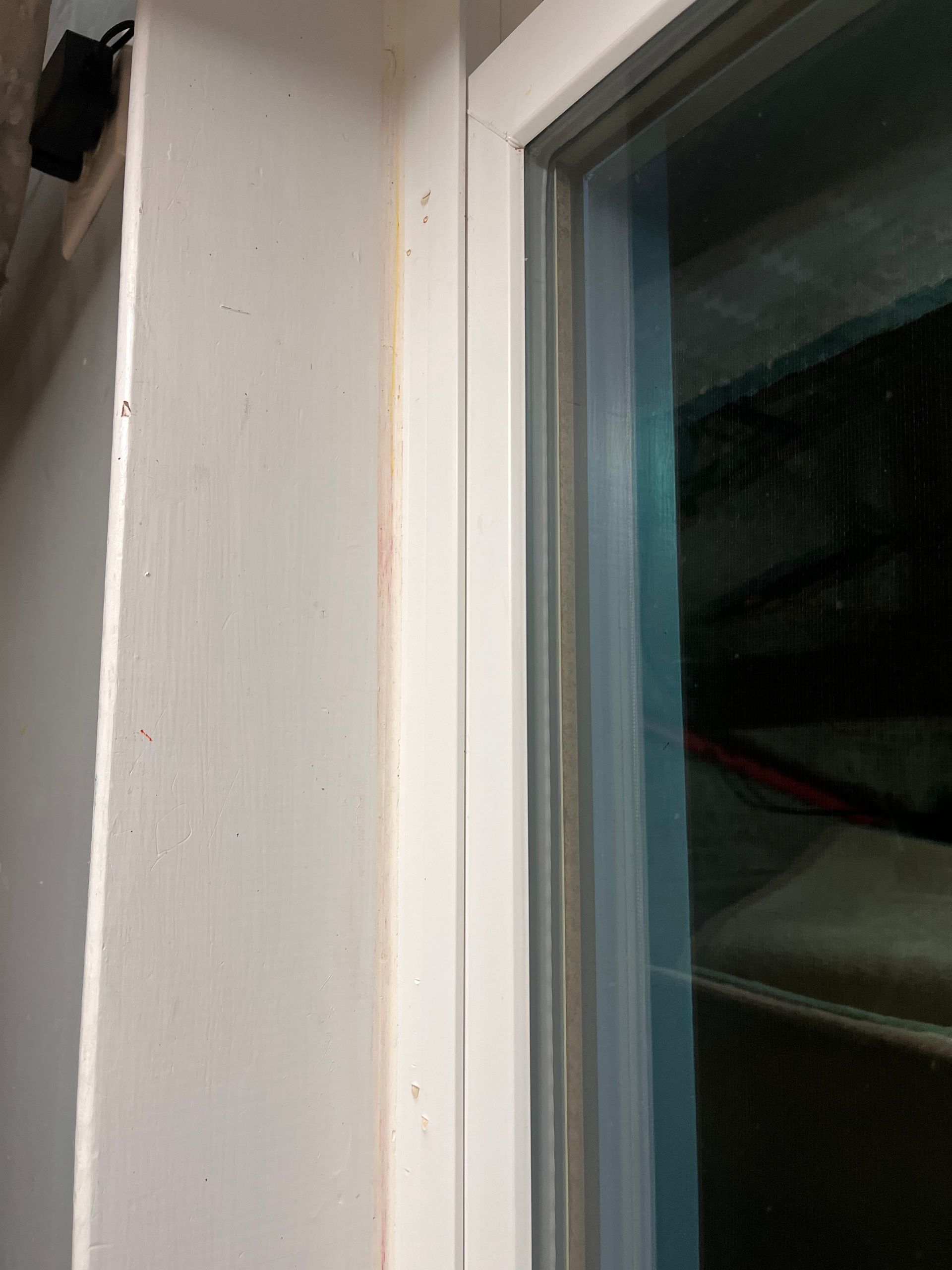 White painted wall and window frame with a thin, vertical strip of discoloration.