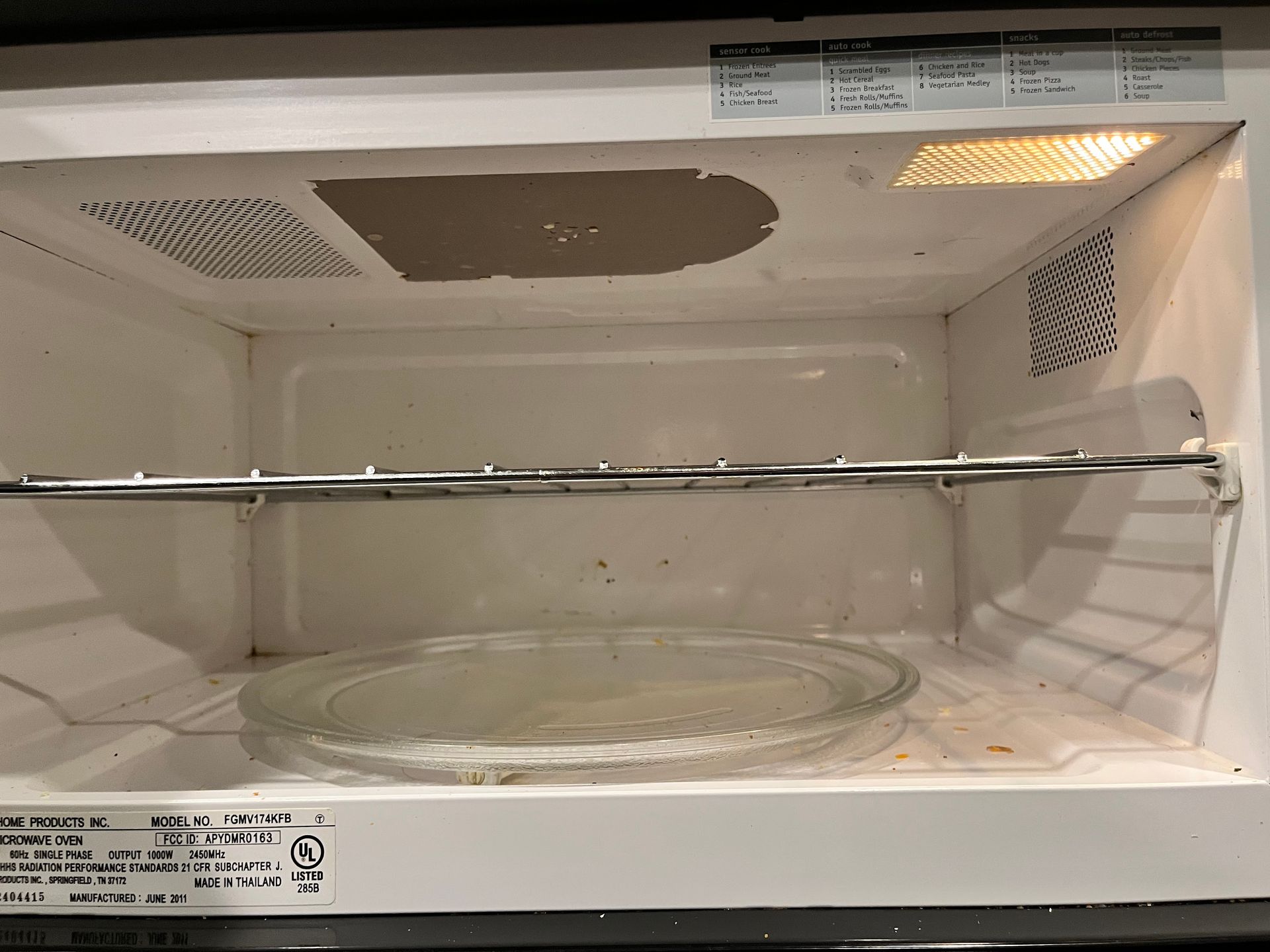 Inside of a white microwave oven. A glass plate sits on the bottom, and a metal rack is above it. The light is on.