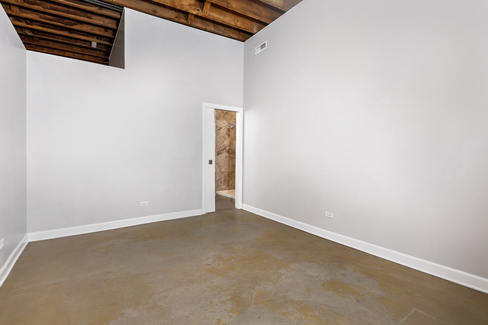 An empty room with white walls and a door leading to a bathroom.