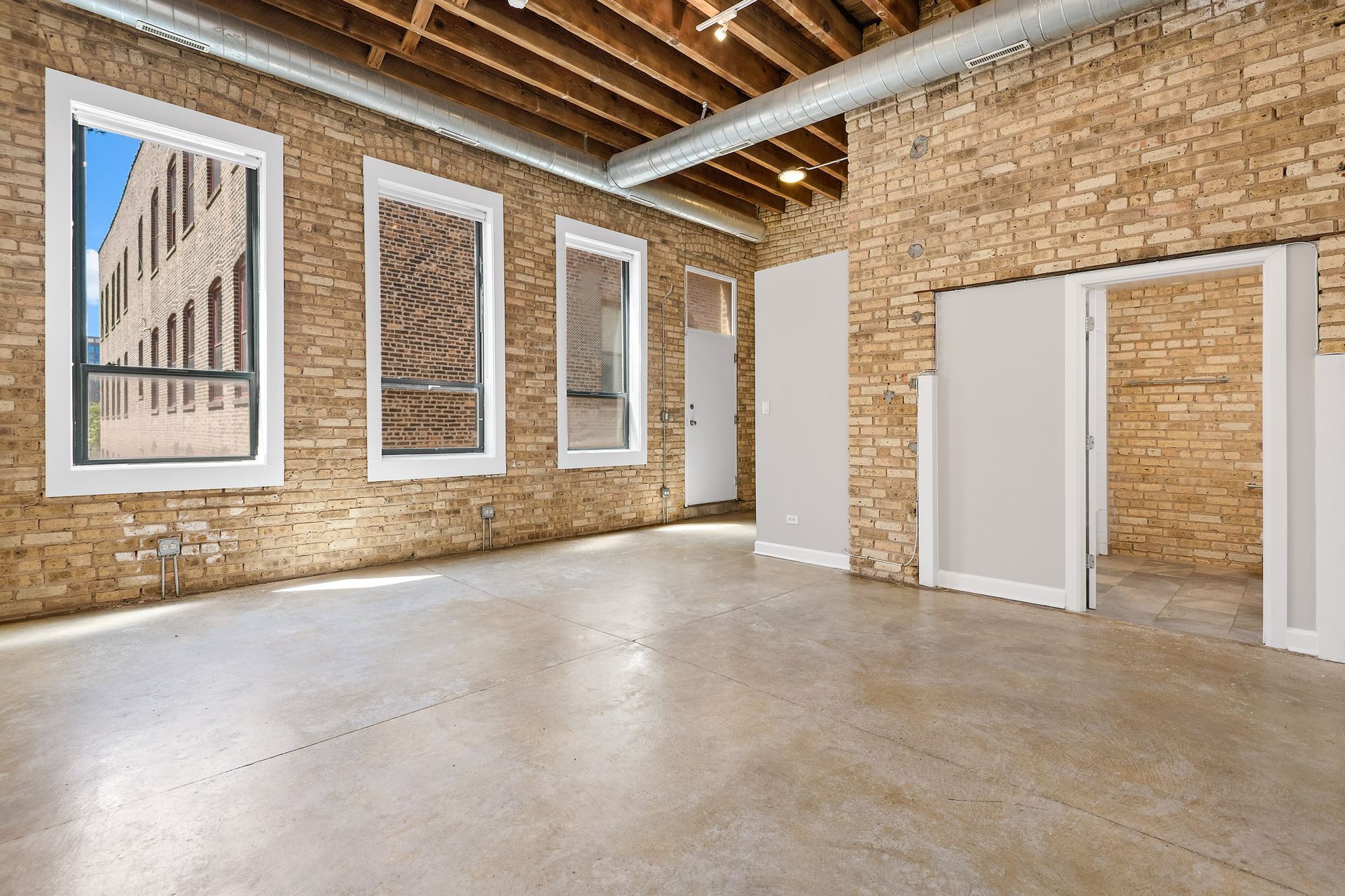 A large spacious apartment lviing room with brick walls and white doors.
