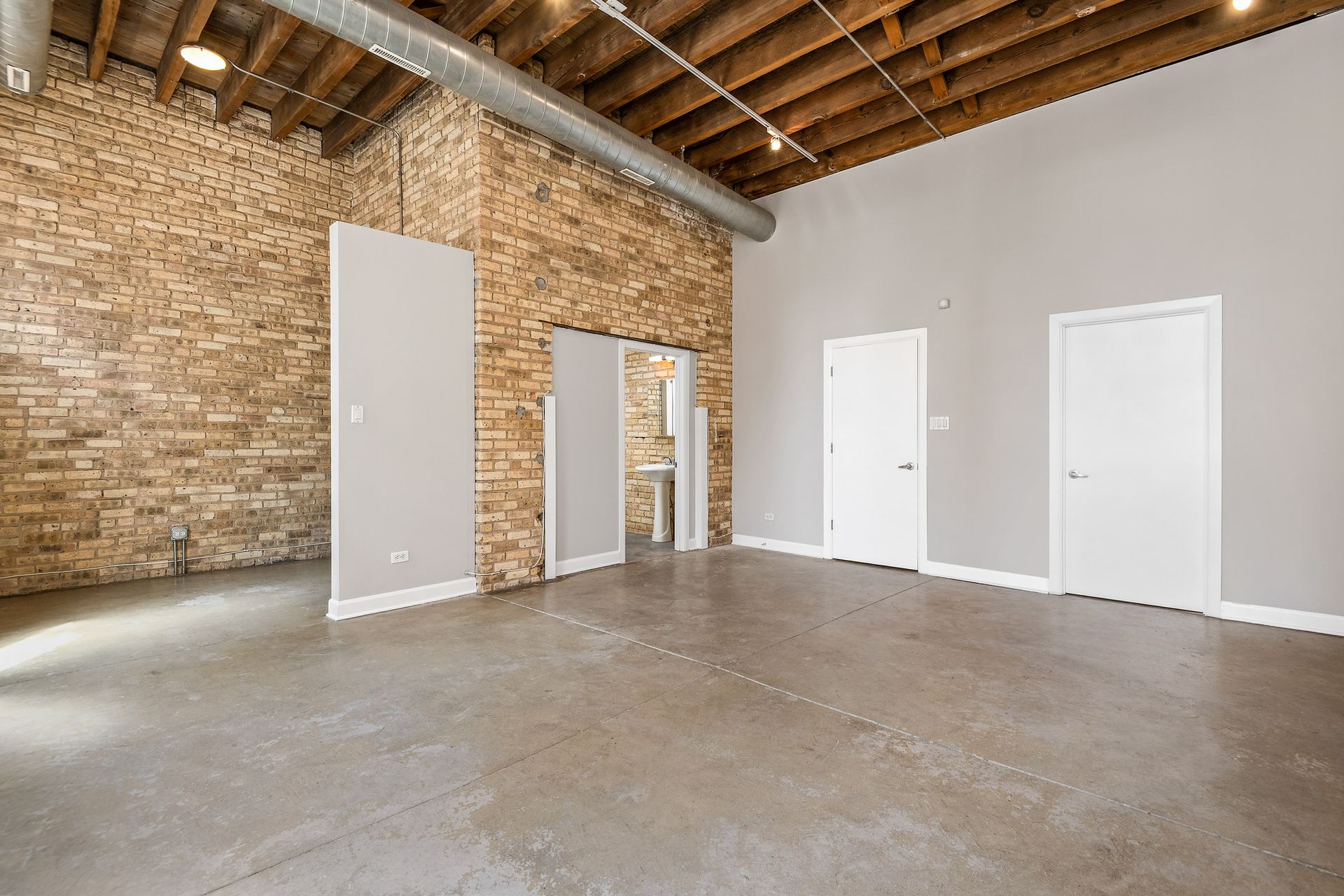 An empty living room with a brick wall and white doors.